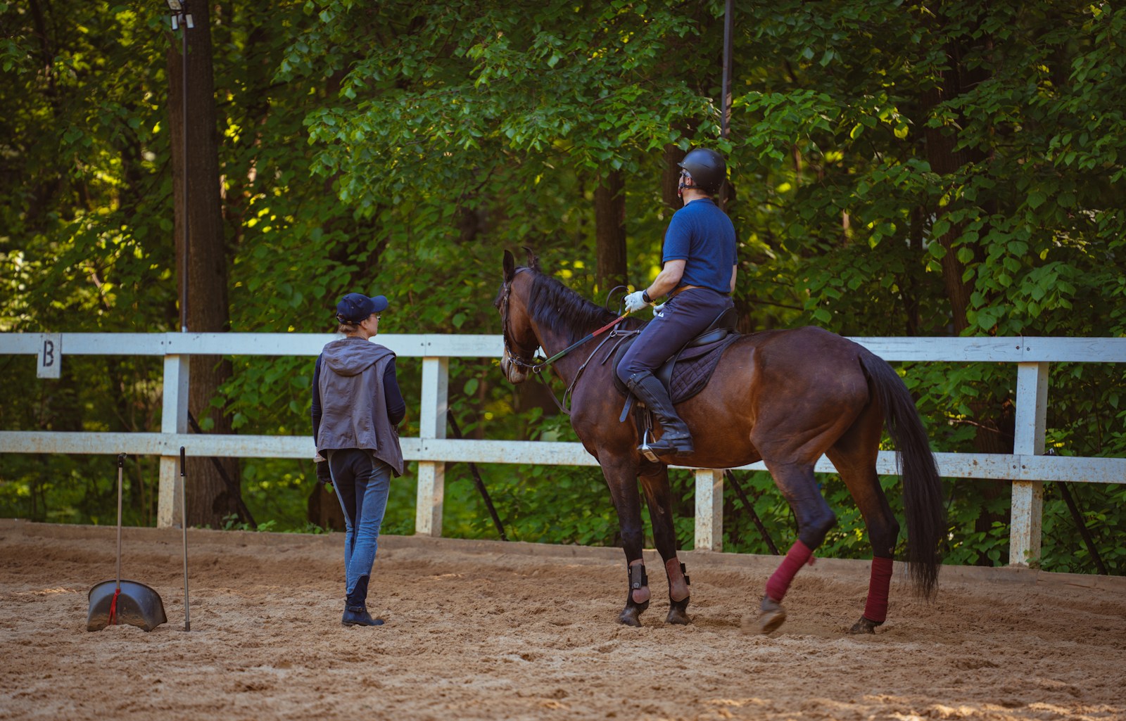 A person rides a horse while another watches.